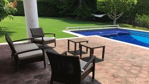 An outdoor patio area with a pool, hexagonal tiles, wicker furniture, and a grassy lawn. - GREAT HOUSE LA MAGDALENA TEQUISQUIAPAN (Magdalena)