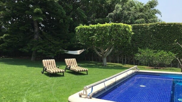 A swimming pool with two lounge chairs and a neatly trimmed hedge. - GREAT HOUSE LA MAGDALENA TEQUISQUIAPAN (Magdalena)