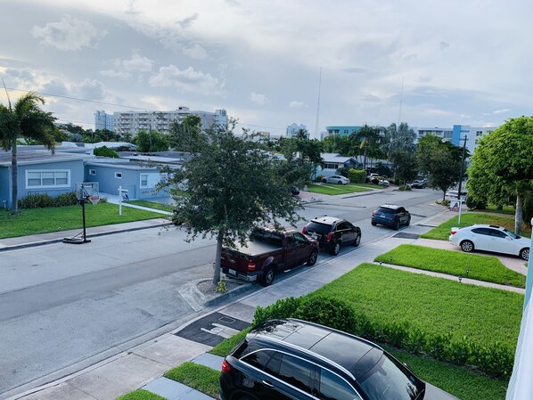 A residential street with houses, a basketball hoop, and parked cars.