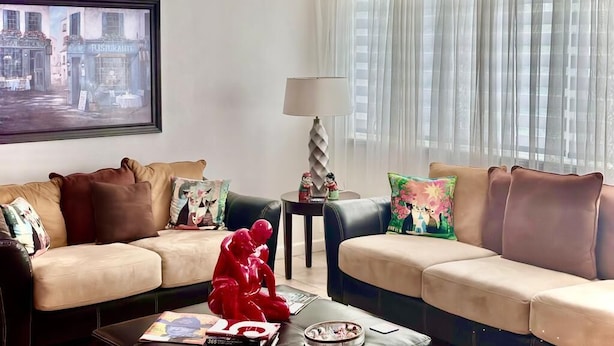 Un salon avec deux canapés, une table basse, une lampe et un tableau encadré au mur.