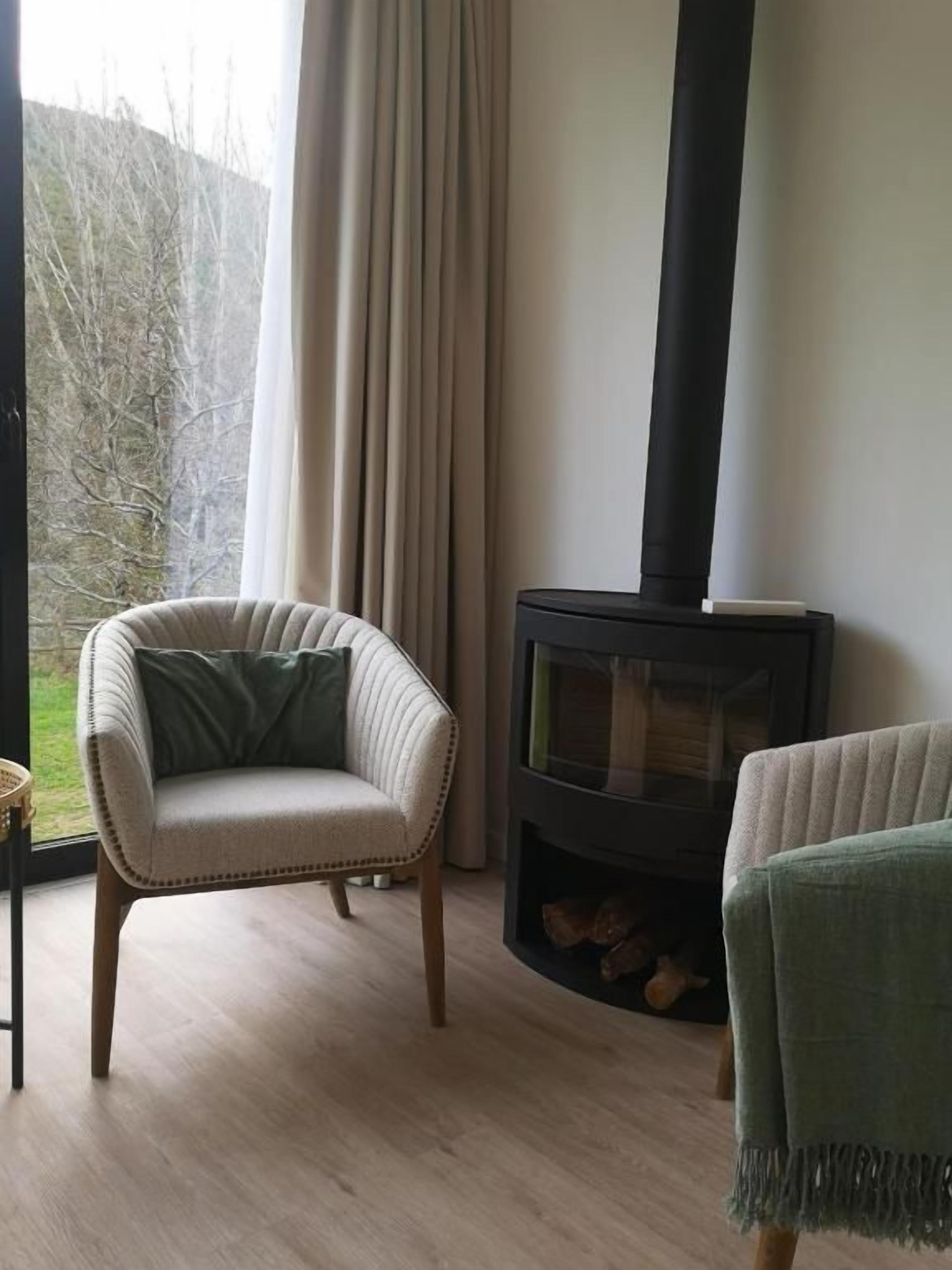 A room with a fireplace, a chair, and a view of the outdoors.