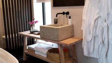 A bathroom with a wooden vanity, a large bathtub, and white towels.