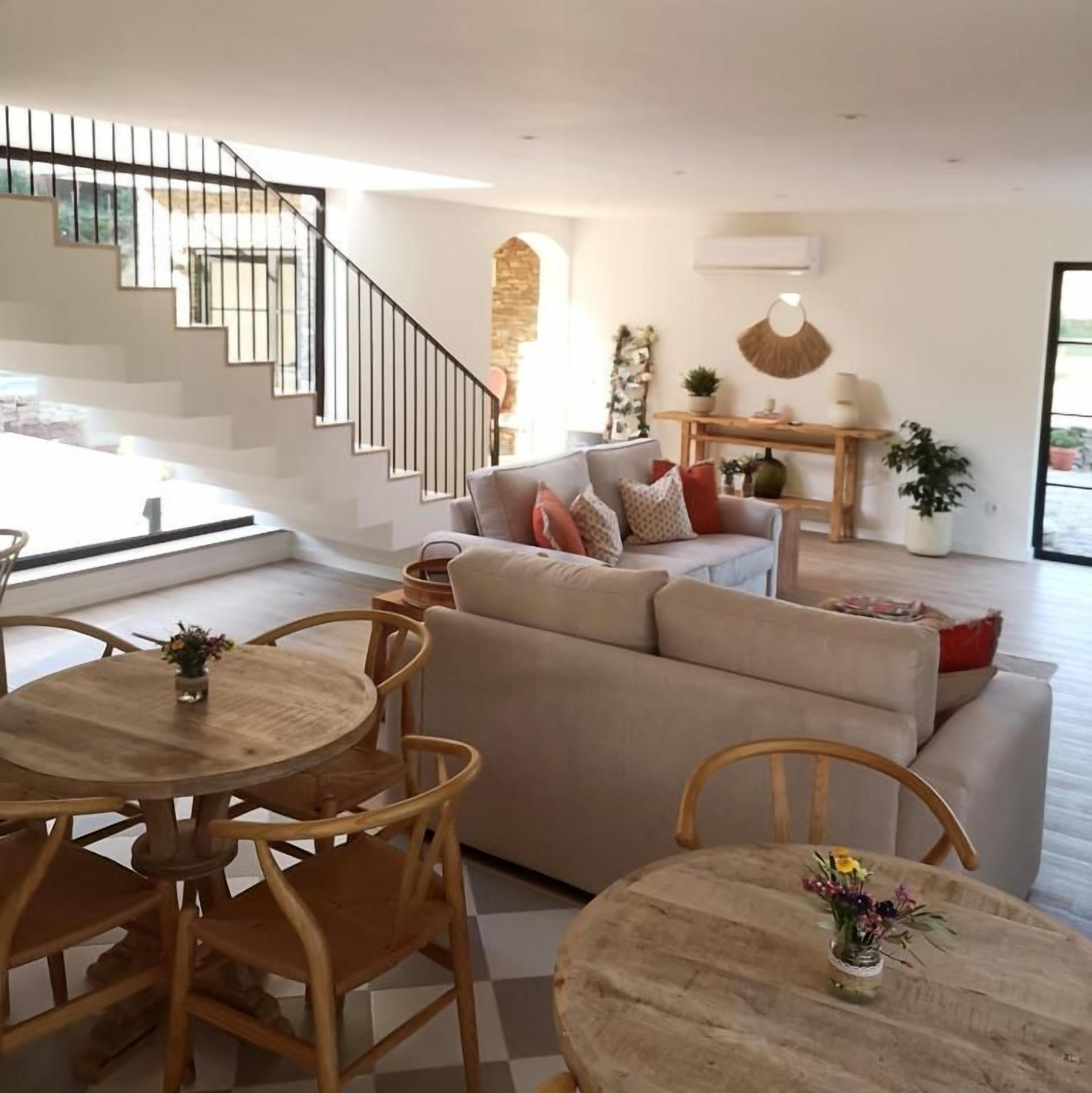 Un salon moderne avec un escalier, un ensemble de canapés et un coin repas doté de meubles en bois.