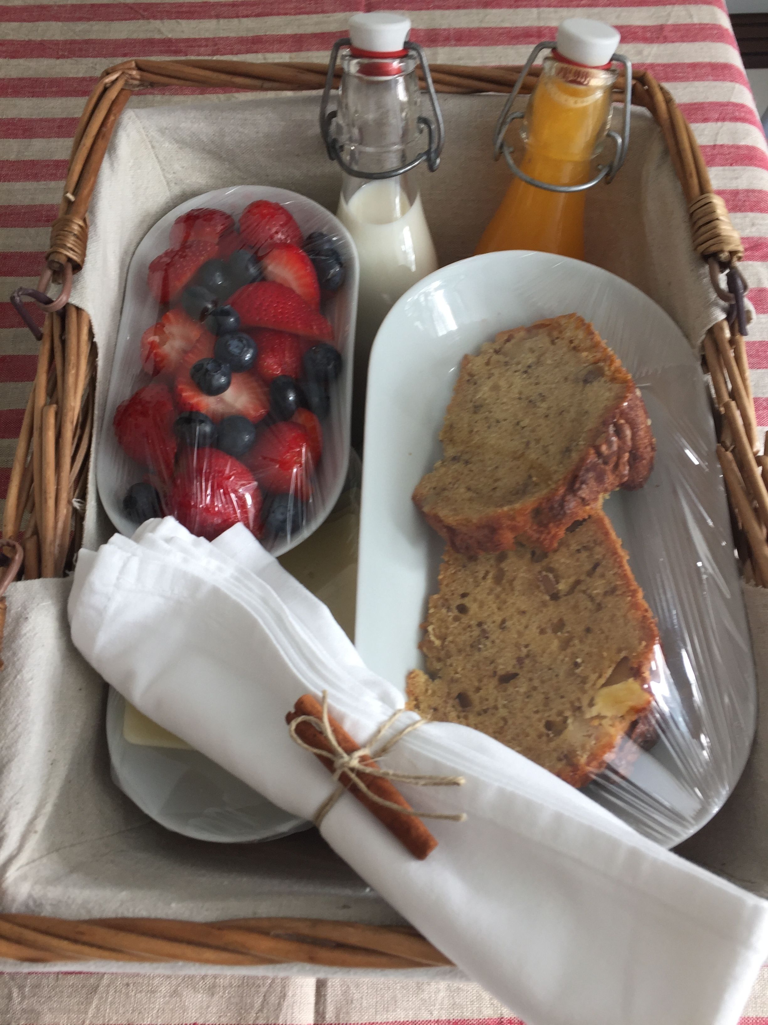 En bakke med brød, en skål med jordbær og blåbær, samt to flasker mælk og juice.