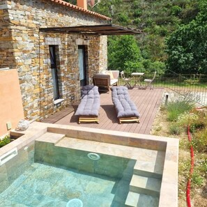A stone building with a pool area, outdoor seating, and a view of greenery. - Quinta das Levadas Country House & Nature (Oliveira do Hospital)
