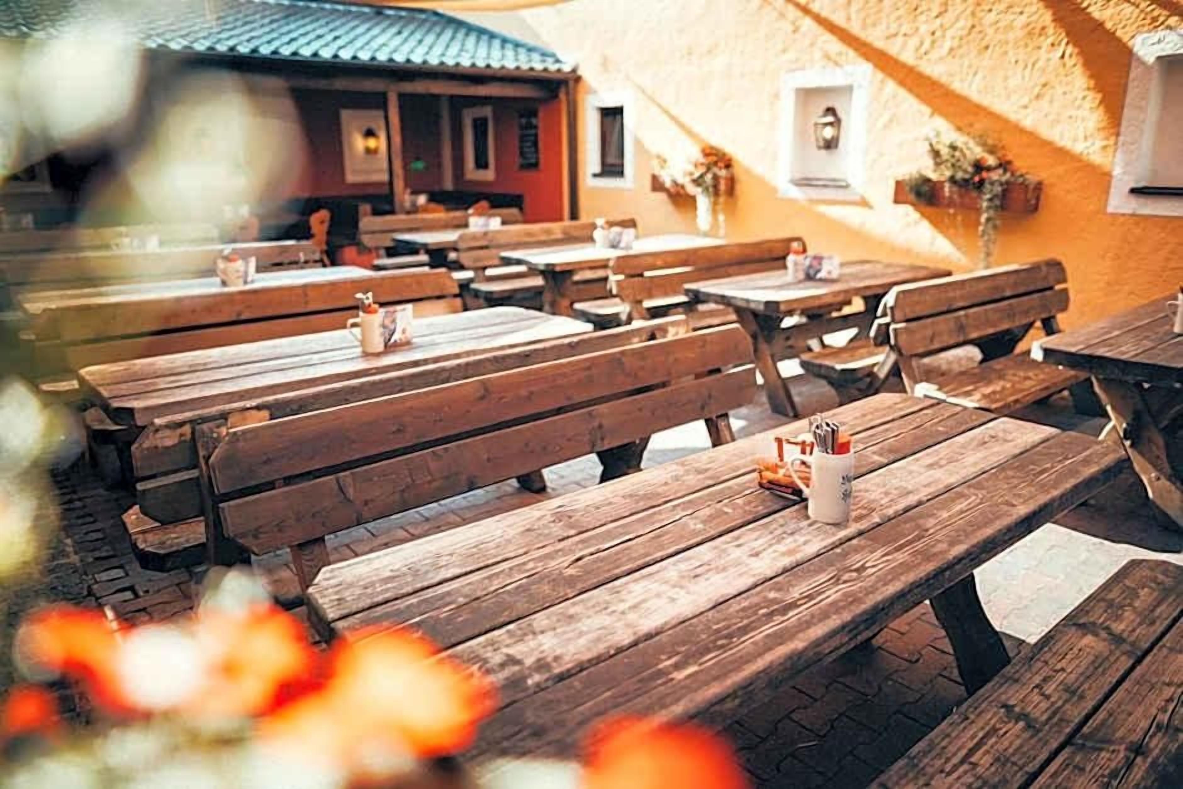 An outdoor seating area with wooden benches and tables, some with condiments.