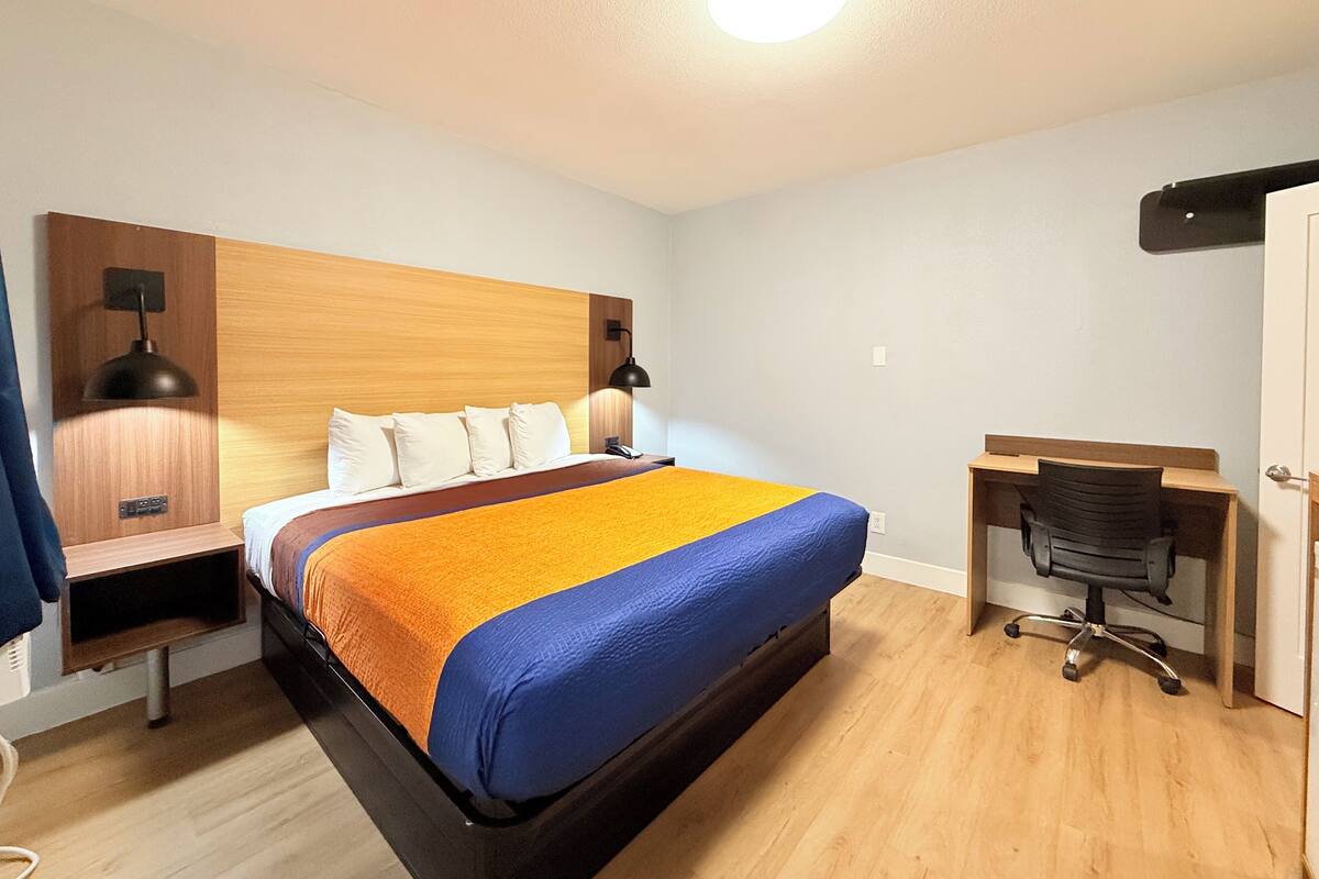 Una habitación de hotel con cama, mesitas de noche, escritorio y silla.