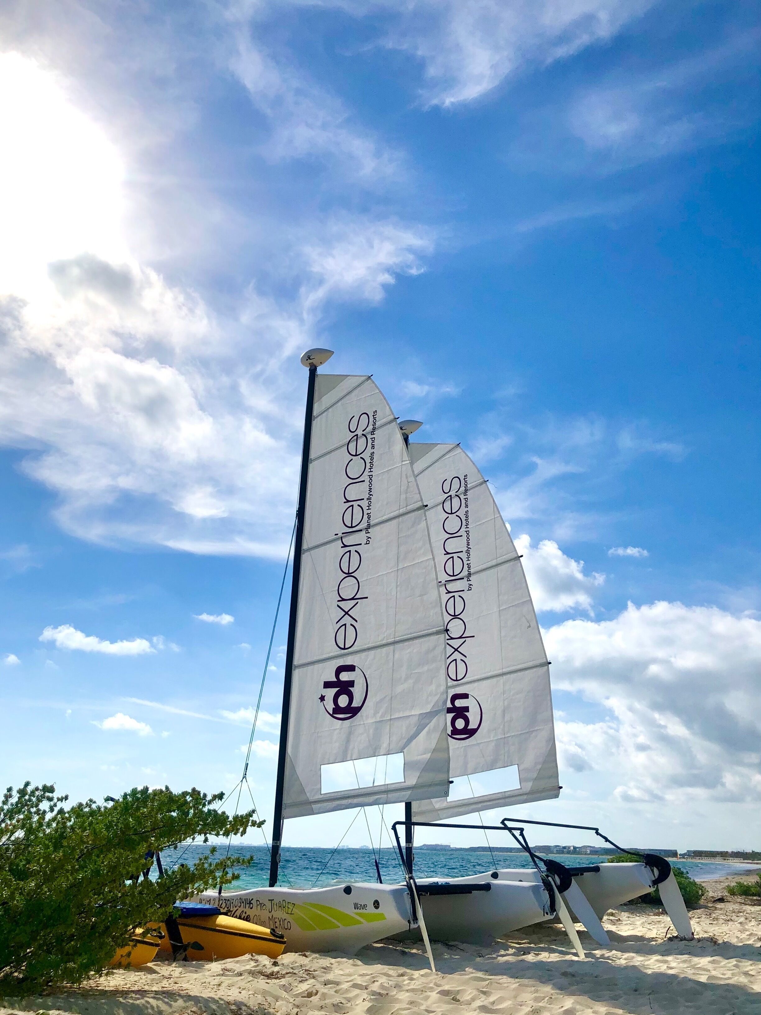 A sailboat with a large sail on a beach.