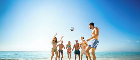 A group of people playing soccer on a beach.