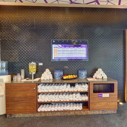 A reception desk with a digital display, water dispensers, and neatly arranged towels.