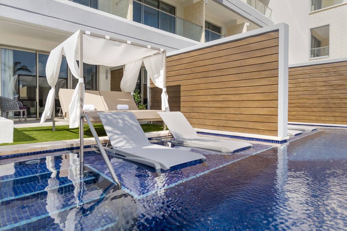 A modern pool area with lounge chairs and a canopy.