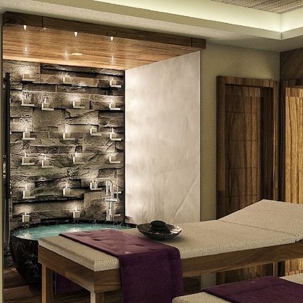A spa room with a wooden wall, a stone wall with candles, a green wall with a star, and a massage table.