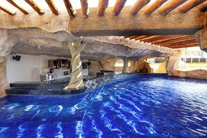 An indoor swimming pool with a unique rock-like ceiling and a bar area. - Planet Hollywood Cancun by Royalton, An Autograph Collection All-Inclusive Resort (Costa Mujeres)