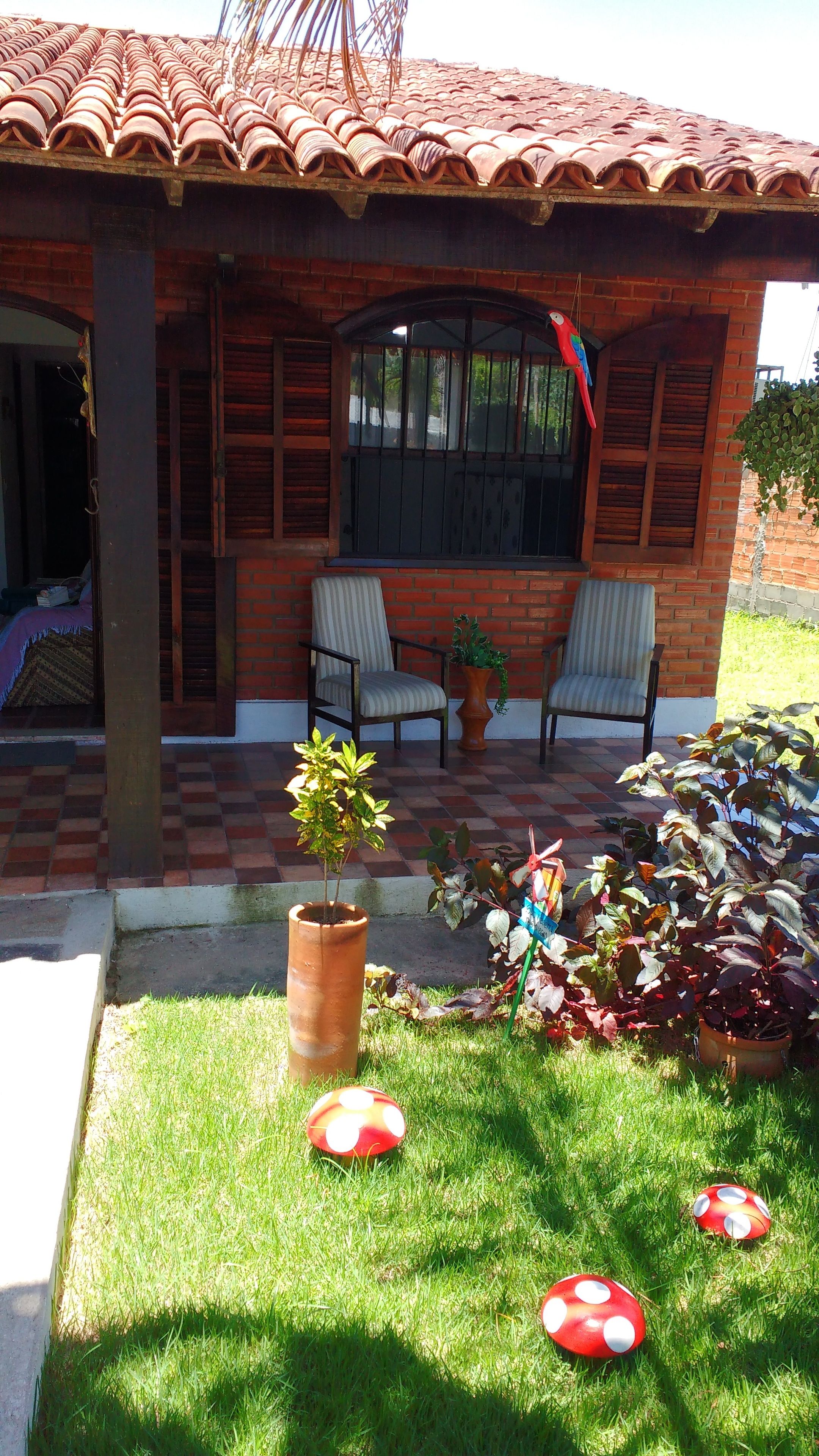Ein Haus mit Ziegeldach, zwei Stühlen, einem Blumentopf und einer Rasenfläche mit Pilzen.
