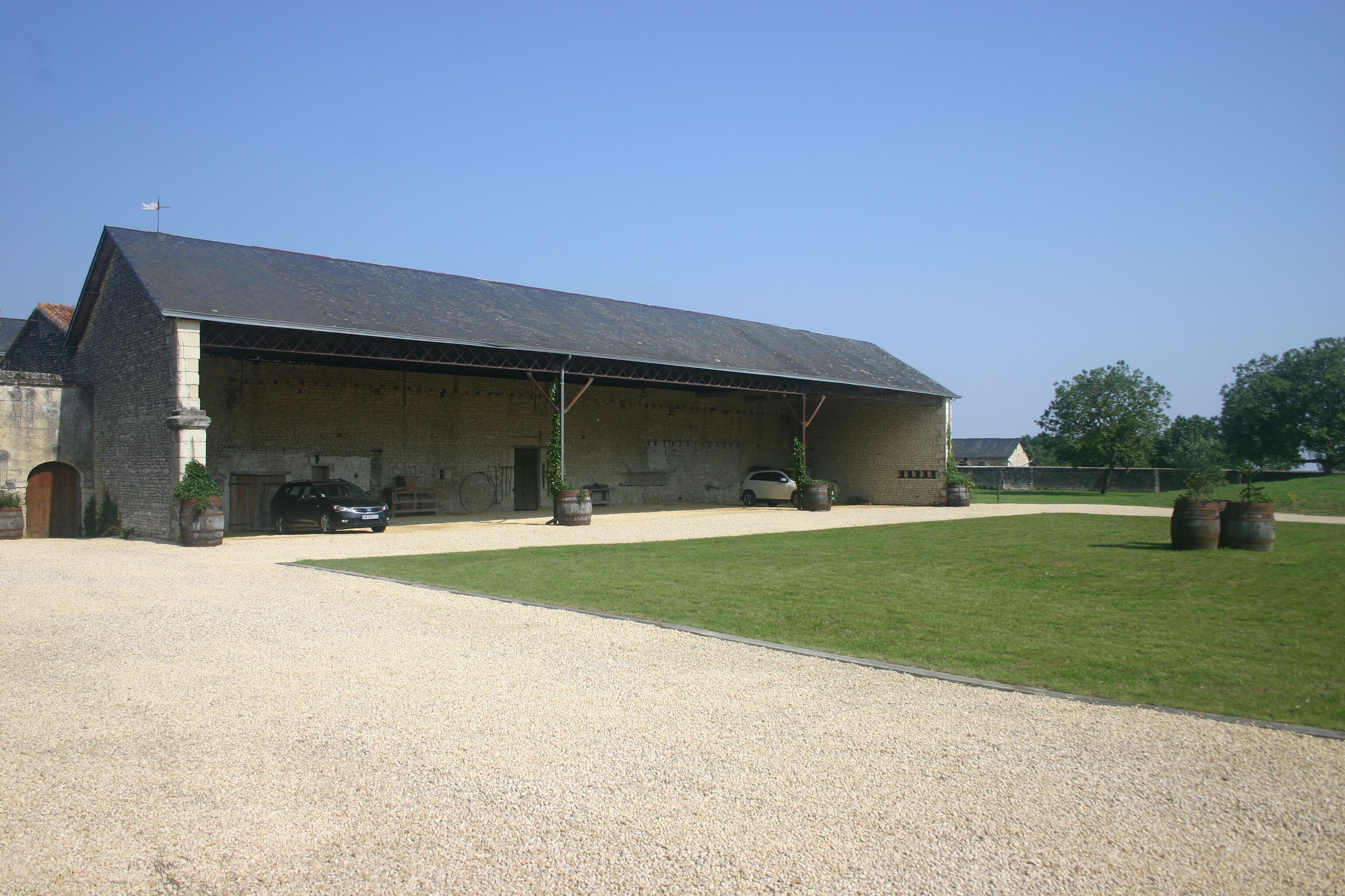 A large, single-story building with a sloped roof, a gravel driveway, and a well-maintained lawn.