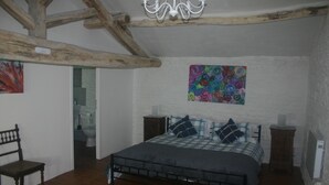 A bedroom with a bed, a wooden chair, a chandelier, and a colorful painting on the wall. - 3 well equipped gites with swimming pool on the Loire Valley/Vienne border (Prinçay)
