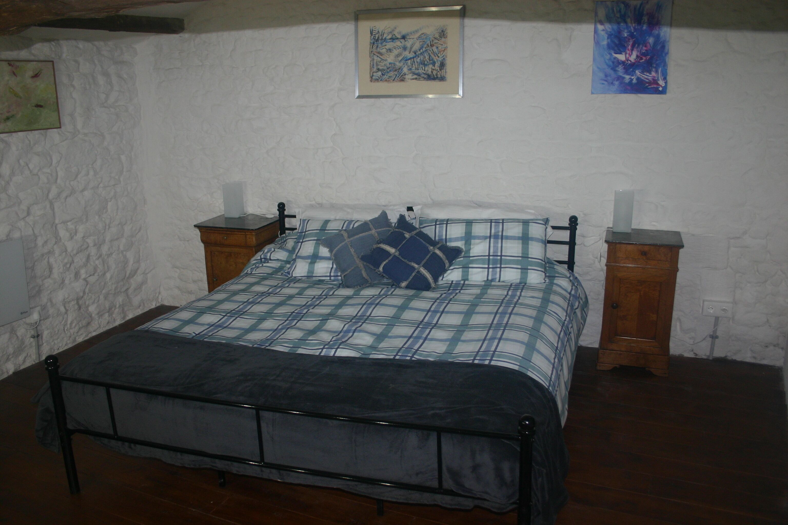 Une chambre à coucher avec un lit, deux tables de chevet et un mur blanc à texture.
