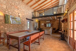 Un intérieur rustique avec un mur en pierre, une table à manger en bois, des bancs et un espace en mezzanine doté d’une rambarde en verre.