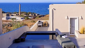 Una terrazza sul tetto con piscina, posti a sedere e vista sul mare.