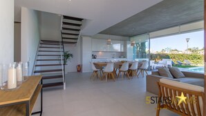 A modern kitchen with a dining area, a staircase, and a view of a swimming pool. - Barcares Suit, Villa 5StarsHome Mallorca (Alcúdia)