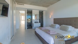 A modern hotel room with a large bed, a TV mounted on the wall, and a view of the outside. - Barcares Suit, Villa 5StarsHome Mallorca (Alcúdia)