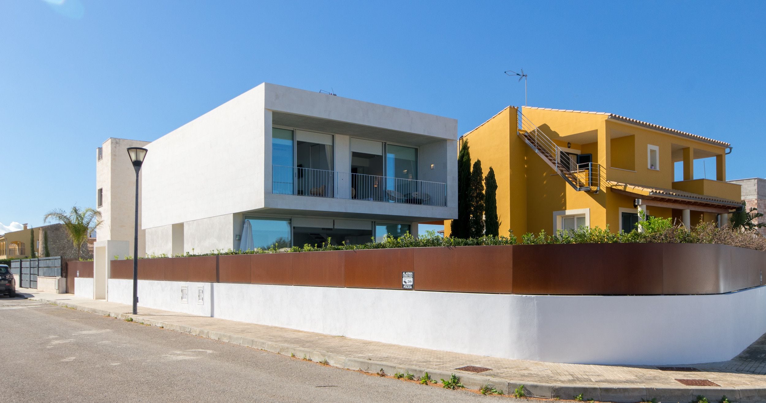 A modern two-story building with balconies and a yellow facade.