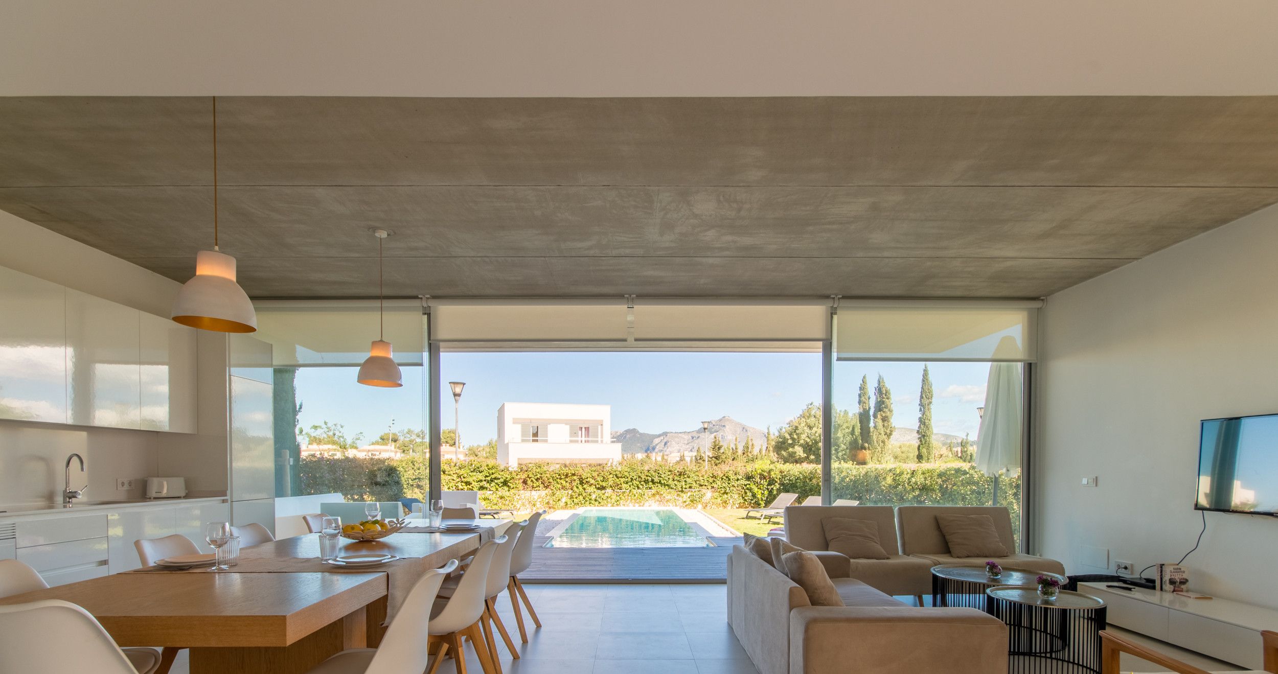 A modern kitchen with a dining area, a pool, and a living room with a sofa and coffee table.