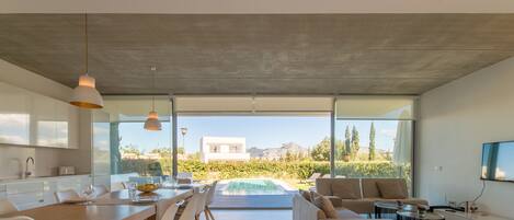 A modern kitchen with a dining area, a pool, and a living room with a sofa and coffee table.