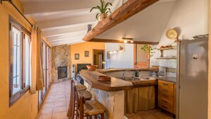 Una cocina con barra de madera, paredes de piedra y techo rústico.