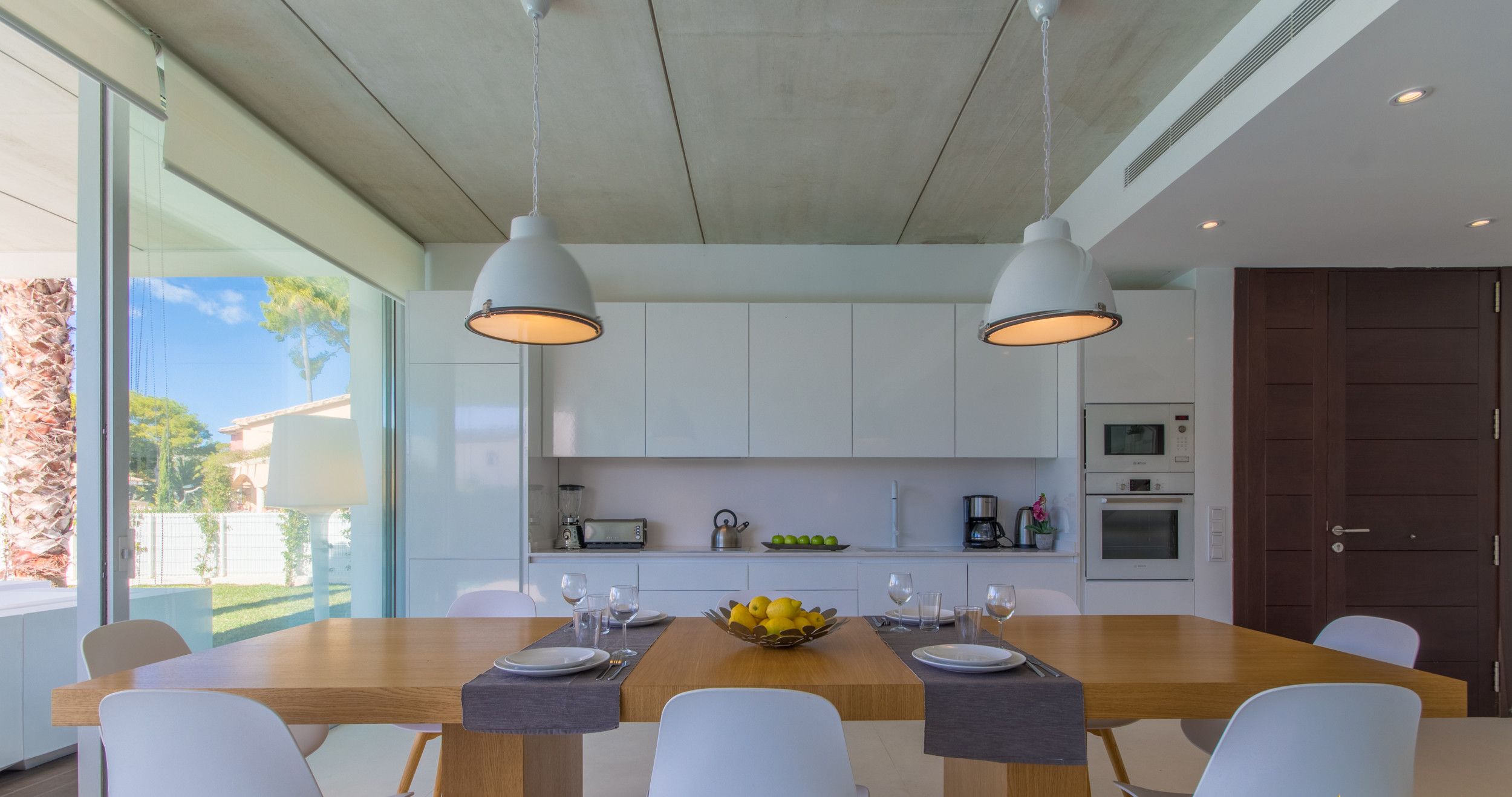A modern kitchen with a central island, white cabinets, and pendant lighting.