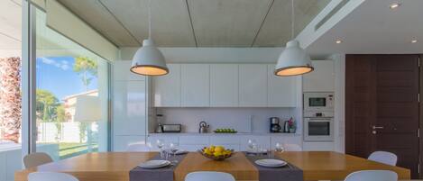 A modern kitchen with a central island, white cabinets, and pendant lighting.
