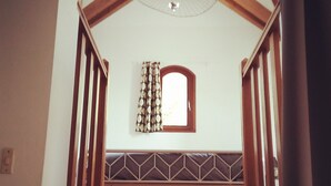 A wooden staircase with a geometric patterned wall and a small window with a decorative frame. - Near Baie de Somme "good authie" (Colline-Beaumont)
