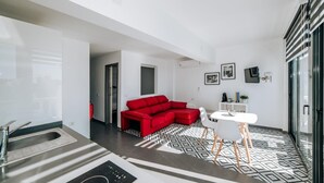 A modern living space with a red sectional sofa, a white dining table, and a patterned floor. - Eterna Primavera Adeje - Relax with Jacuzzi and A/C (adeje)