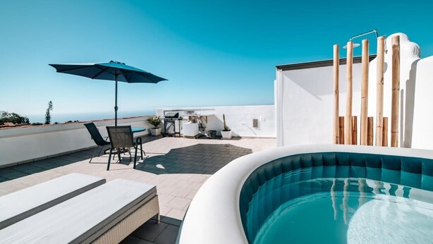 A rooftop pool area with a view of the ocean, a lounge chair, a table with chairs, and a blue umbrella. - Eterna Primavera Adeje - Relax with Jacuzzi and A/C (adeje)