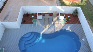 A swimming pool with a wooden deck, surrounded by a white fence, and includes outdoor seating and planters. - Pierhouse Bed & Breakfast (Kill Devil Hills)