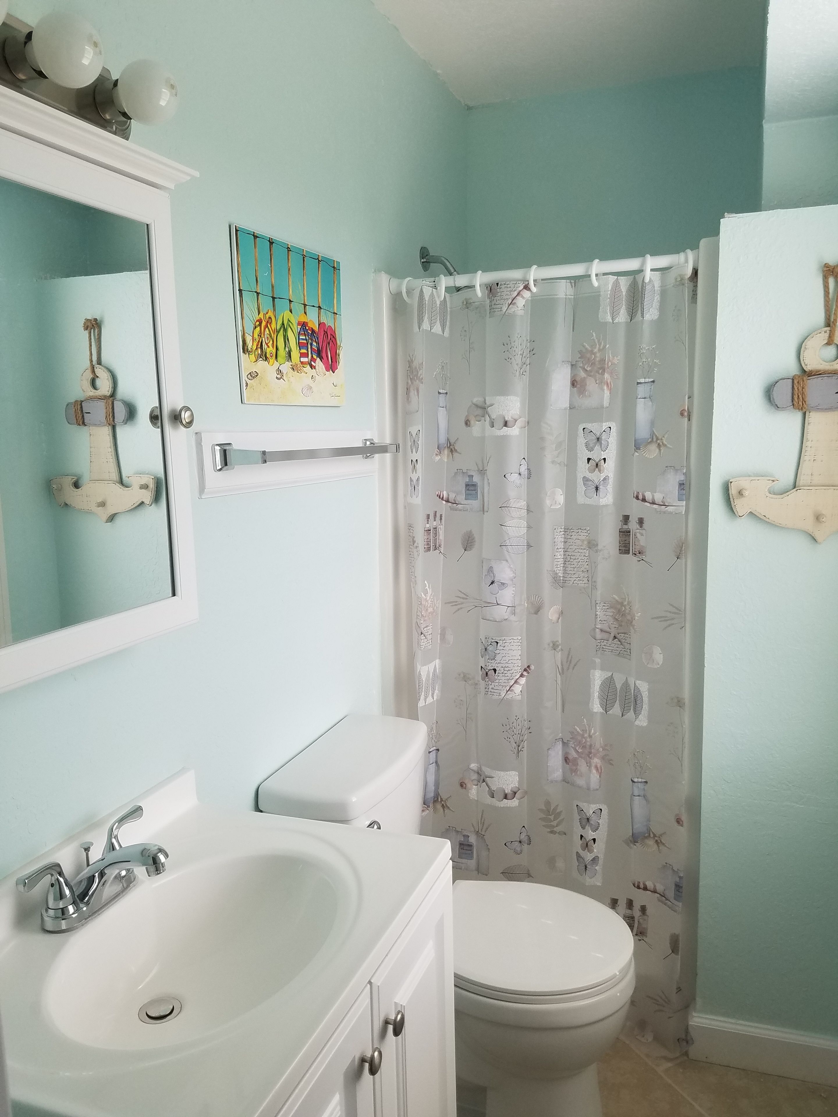 A bathroom with a white sink, a toilet, and a shower curtain with a nature-themed pattern.