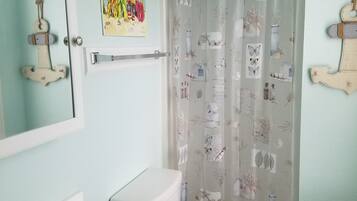 A bathroom with a white sink, a toilet, and a shower curtain with a nature-themed pattern.