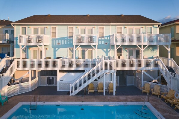 A two-story building with a pool and outdoor seating. - Five Bedroom Oceanfront Triplex Unit D (Ocean Isle Beach)