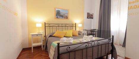 Un dormitorio ordenado con cama, mesitas de noche y ventana con cortinas.
