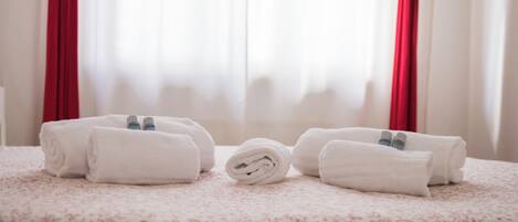 A neatly arranged set of towels on a bed with a floral-patterned bedspread.