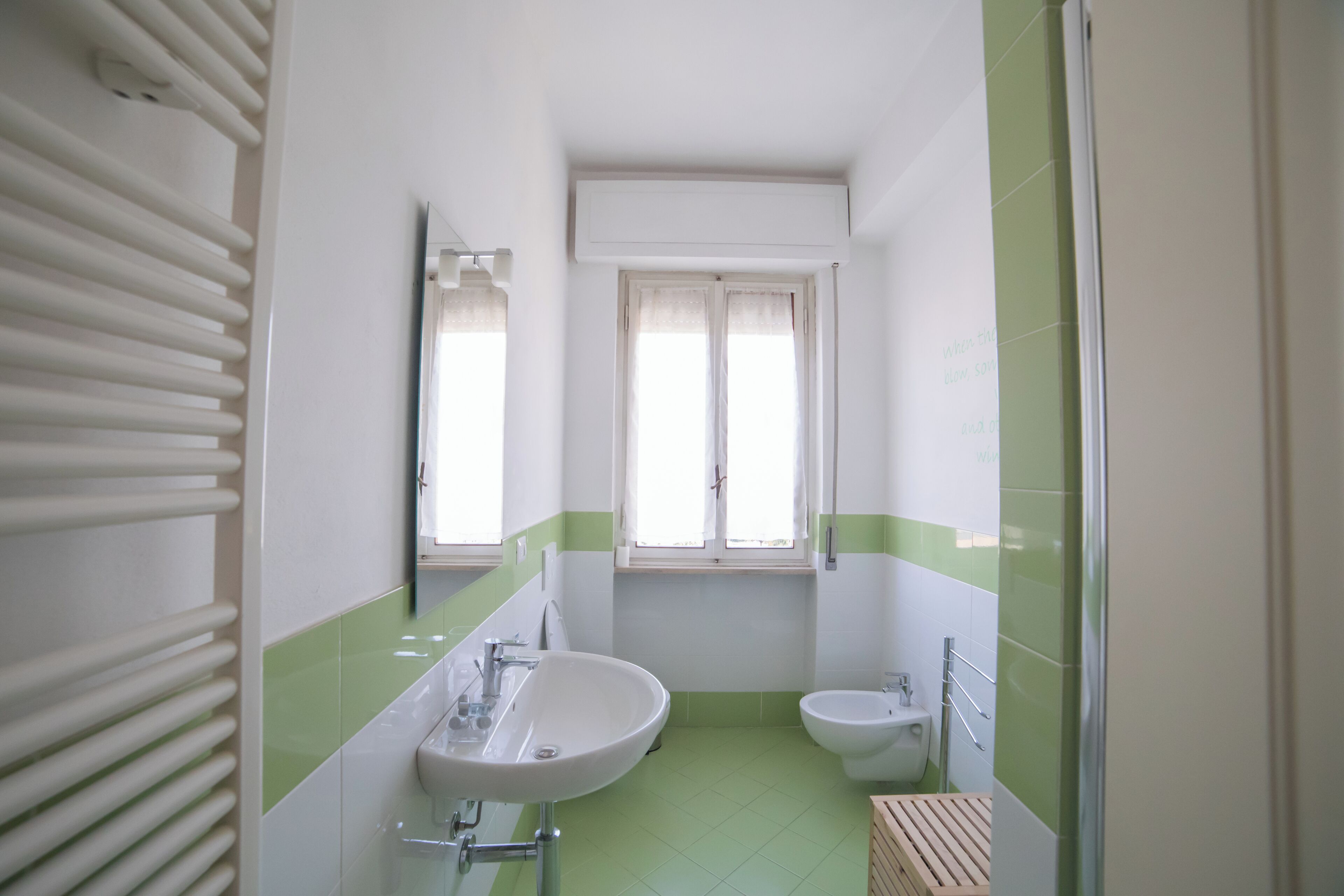 A bathroom with a sink, bidet, and a window.