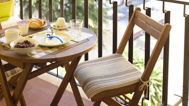 A wooden chair with a striped cushion and a table with breakfast items.