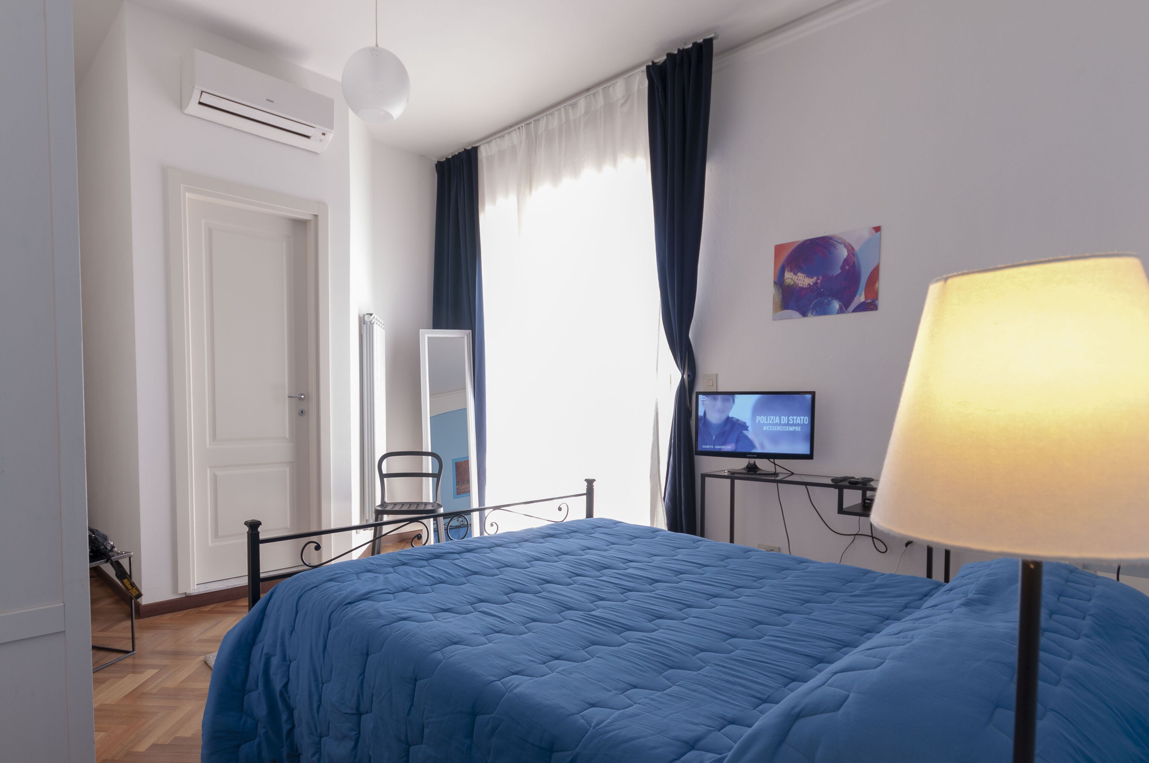 A hotel room with a bed, a TV, a desk, and a lamp.