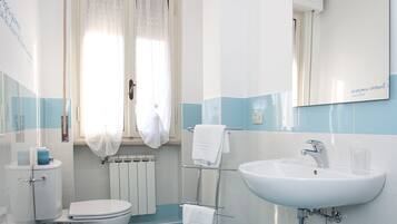 Ein modernes Badezimmer mit Toilette, Bidet, Waschbecken und Spiegel.