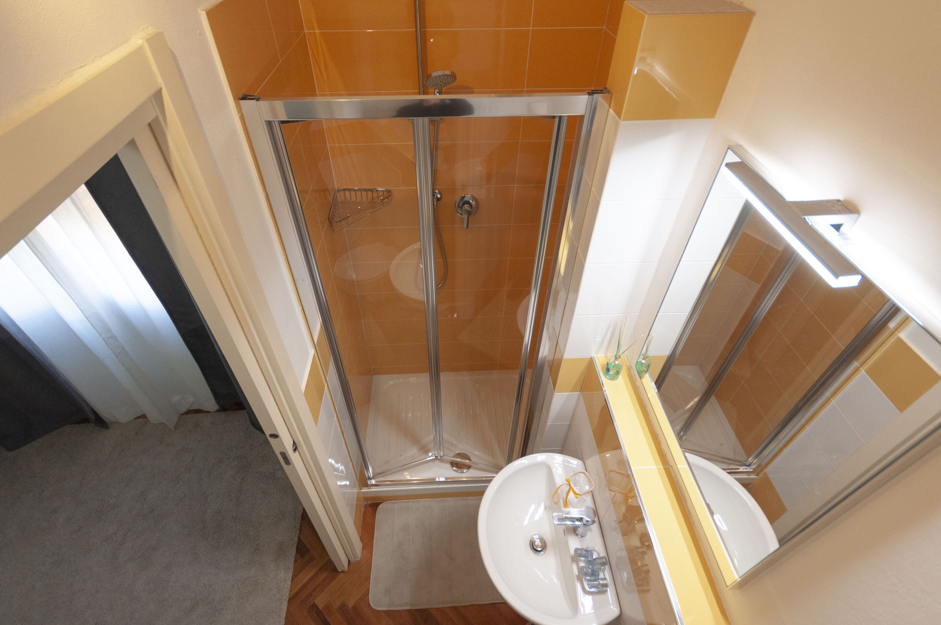 A bathroom with a glass-enclosed shower, a sink, and a mirror.