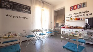 A dining area with tables and chairs, a kitchen in the background, and a wall with a cafe sign and a question "Are you hungry?".