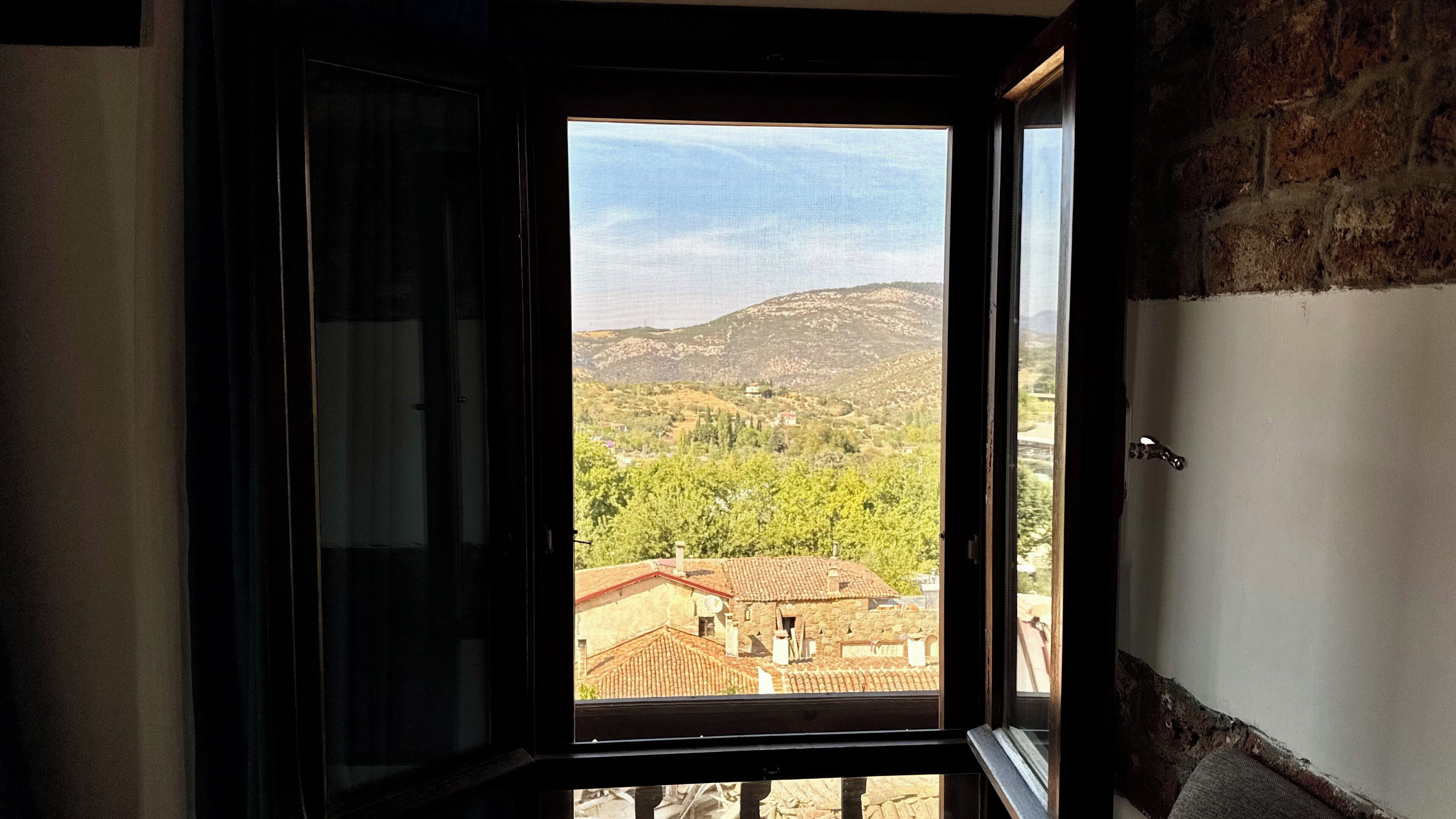 An open door with a view of a mountainous landscape and traditional buildings.