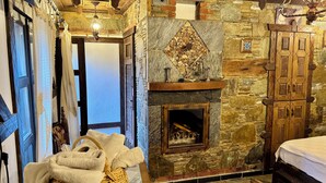 A stone-walled room with a fireplace, a bed, and a wooden wardrobe. - Limaki Konak Sirince (Selçuk)