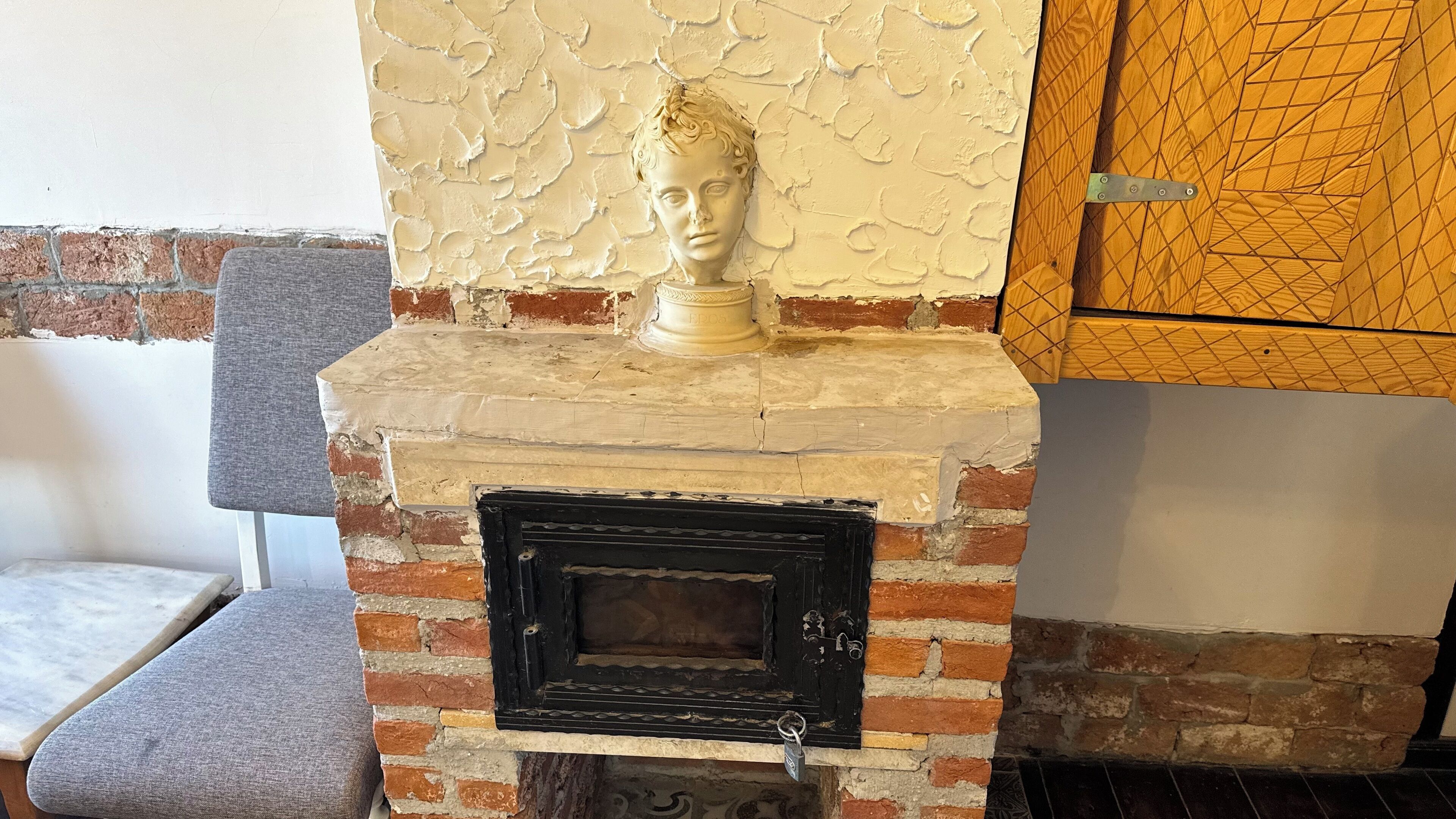 A fireplace with a brick surround and a white decorative panel above it.