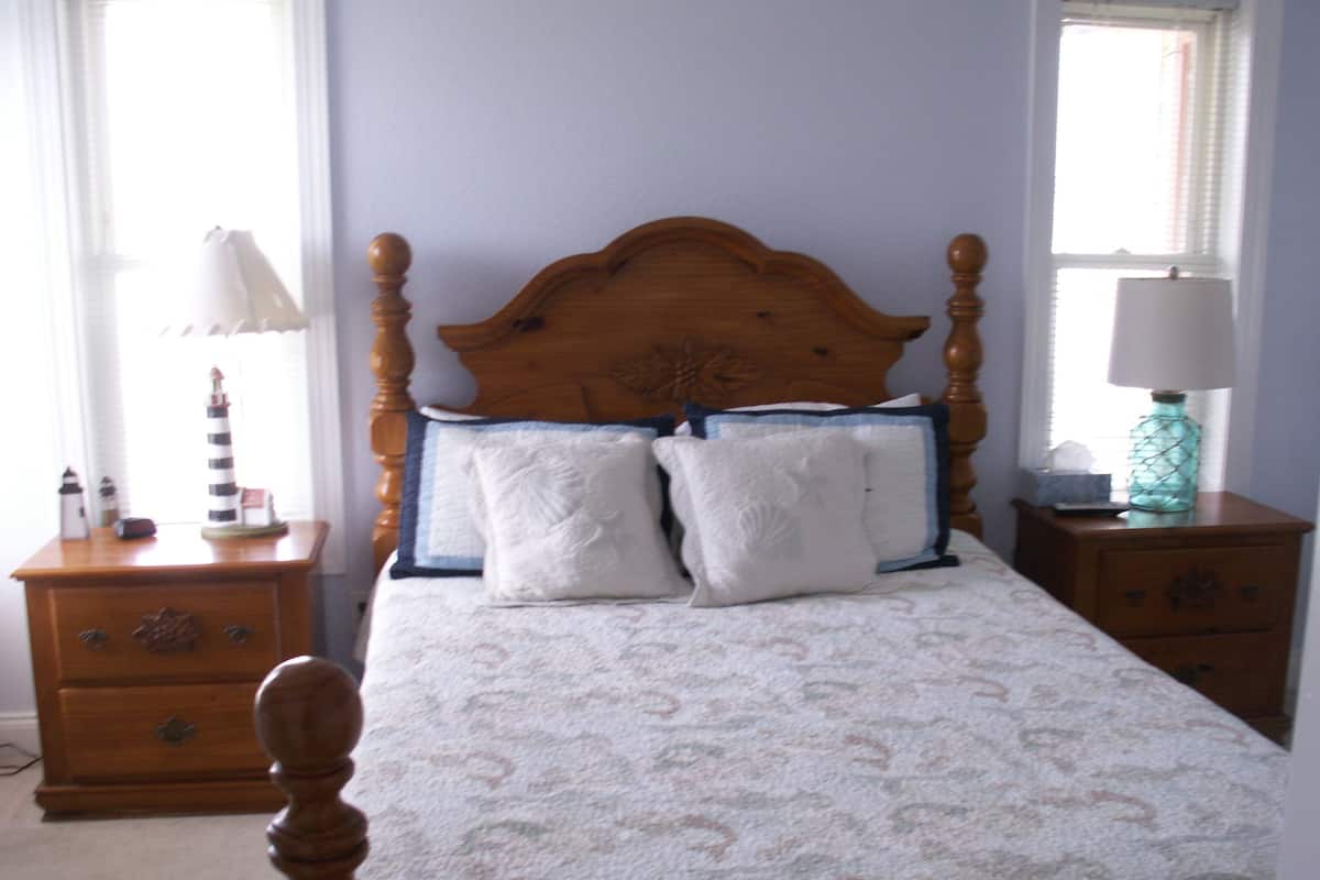 A bedroom with a wooden headboard, two bedside tables, a lamp, and a nightstand.